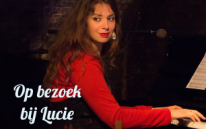 Uitgelichte afbeelding van Lucie spelend op een piano, met op de afbeelding de tekst "Op bezoek bij Lucie"