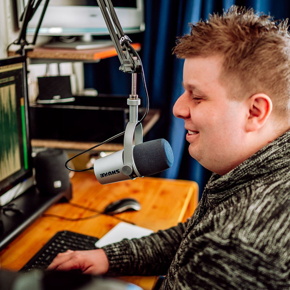 Foto van Ferry zitten voor zijn microfoon en pc-scherm meteen hand op een toetsenbord.